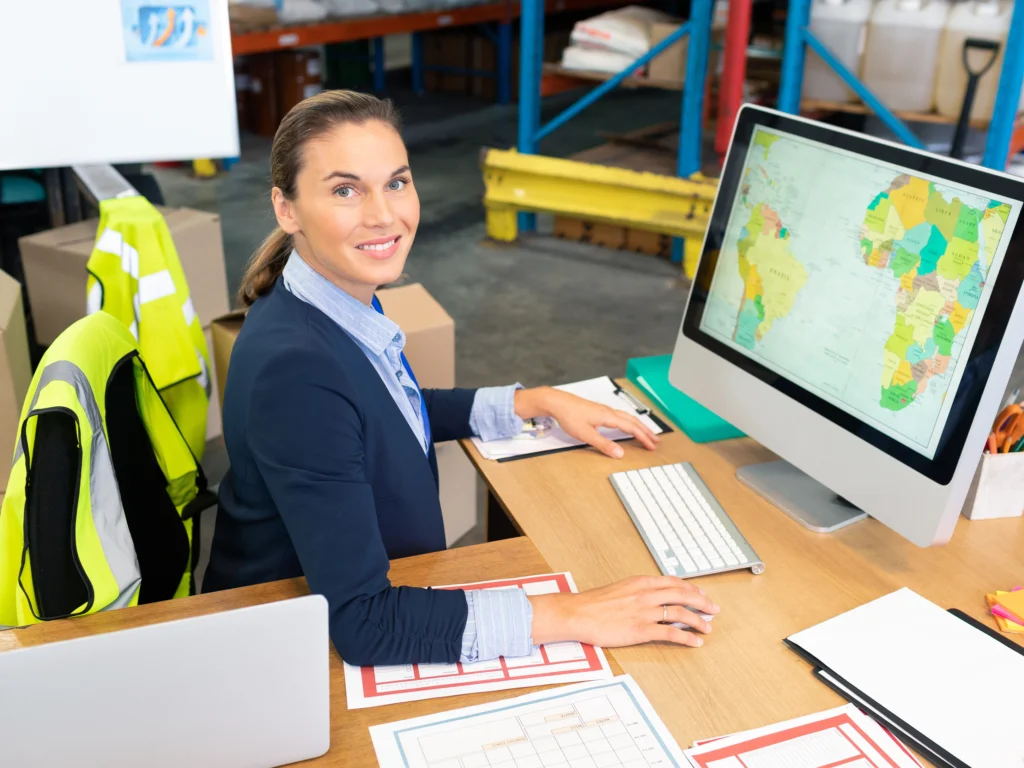 Especialista en logística monitoreando envíos internacionales desde una oficina con mapa de rutas comerciales